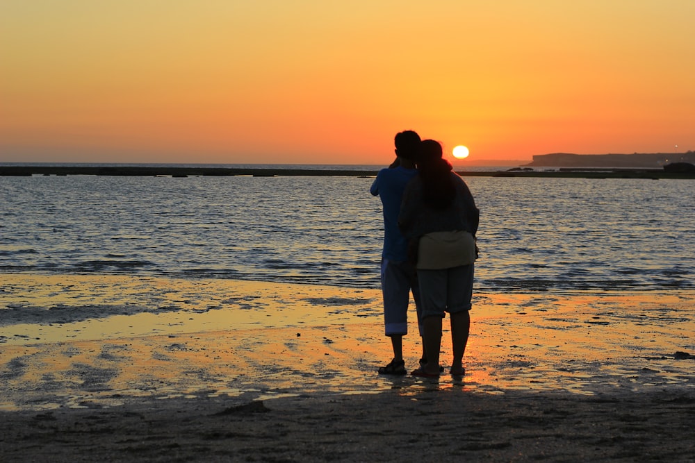 couple standing on beach during sunset