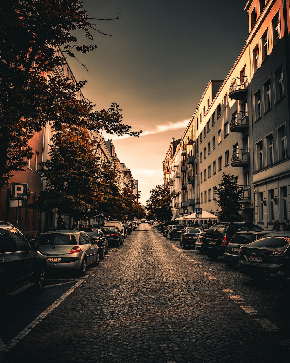 a street lined with parked cars next to tall buildings