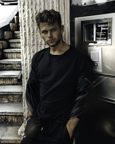 man in black crew neck long sleeve shirt standing beside gray metal cabinet