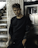 man in black crew neck long sleeve shirt standing beside gray metal cabinet