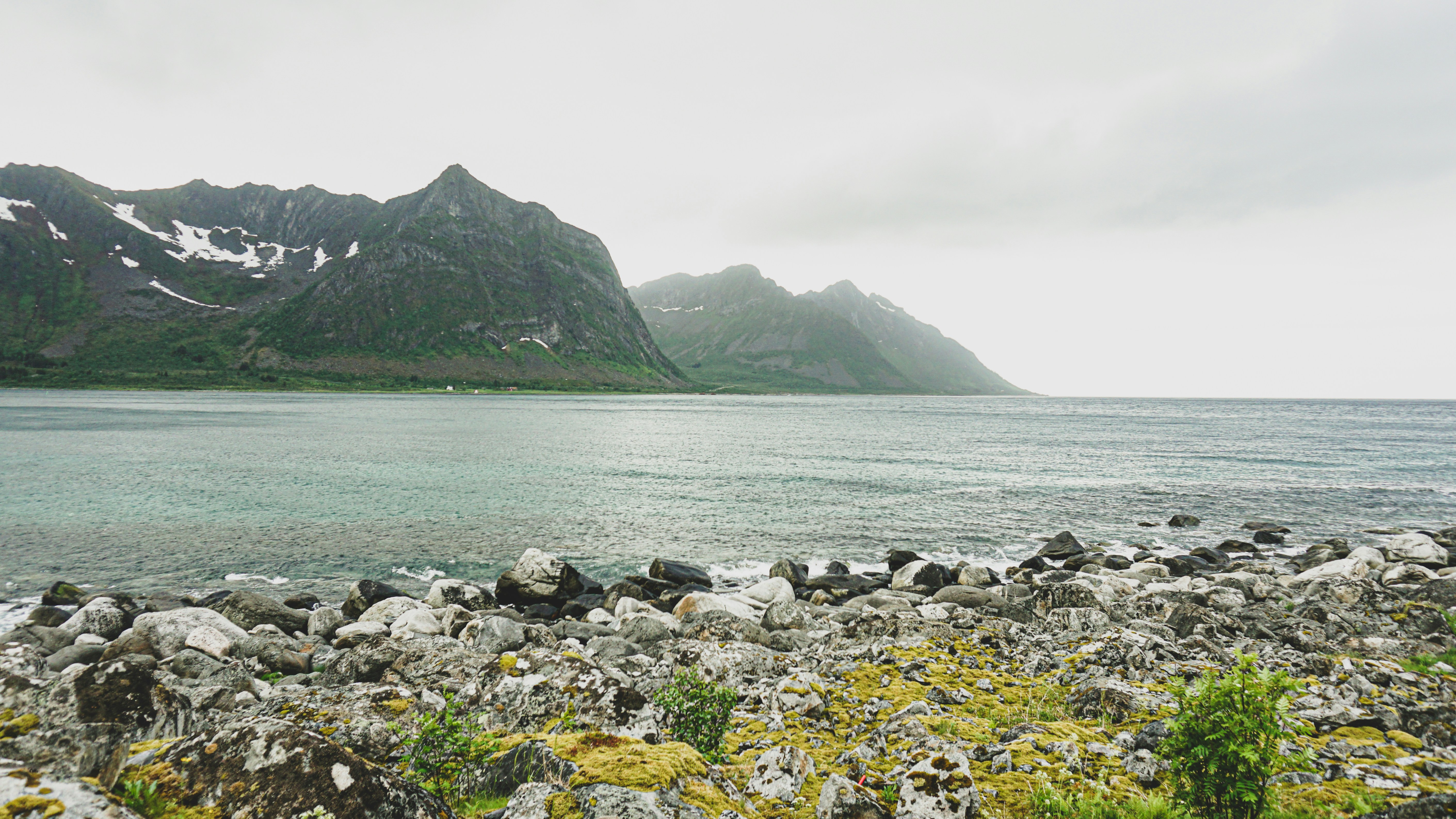 grüner und schwarzer Berg neben dem Gewässer tagsüber