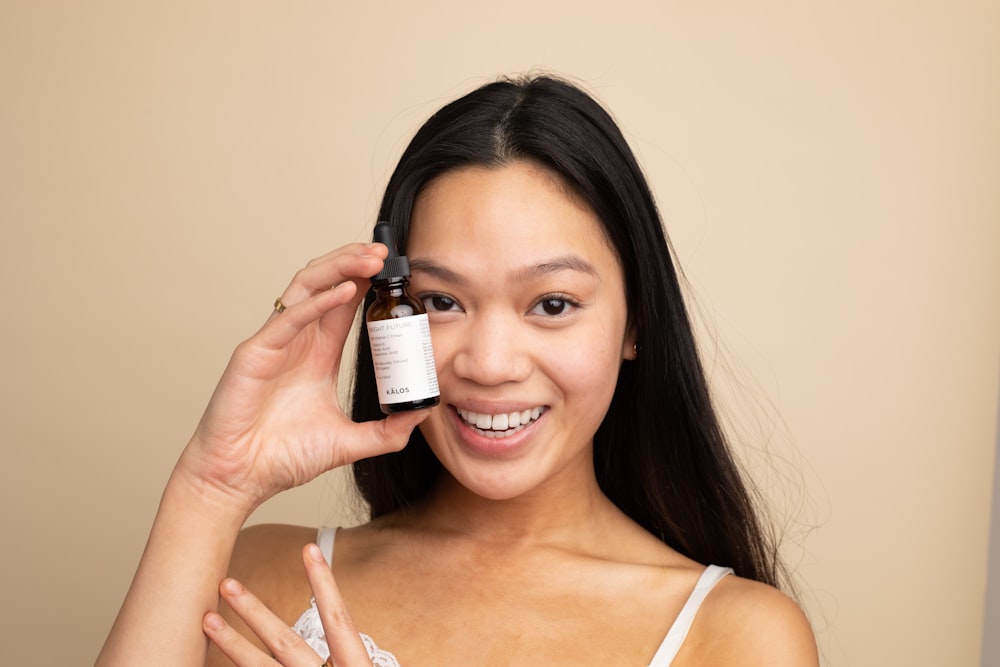 woman in white tank top holding white labeled bottle