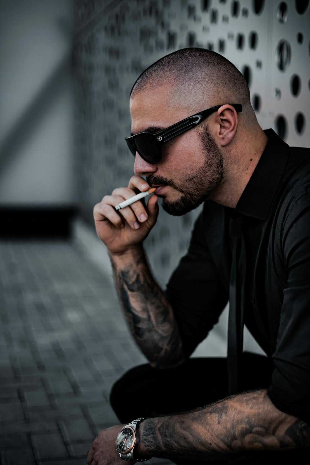 hombre en camisa de vestir negra fumando cigarrillo