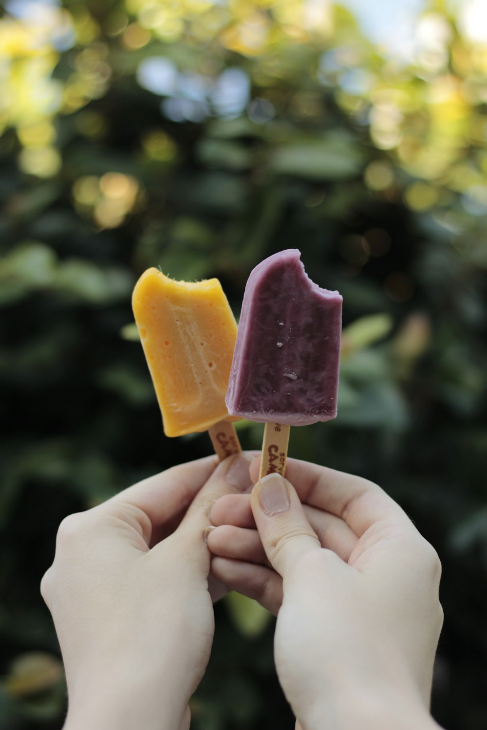 person holding yellow and pink ice cream