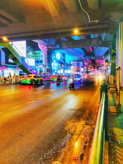 A vibrant city street at night with neon lights reflecting on wet pavement, showcasing urban mobility.