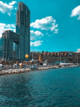 white boat on sea near city buildings under blue and white sunny cloudy sky during daytime