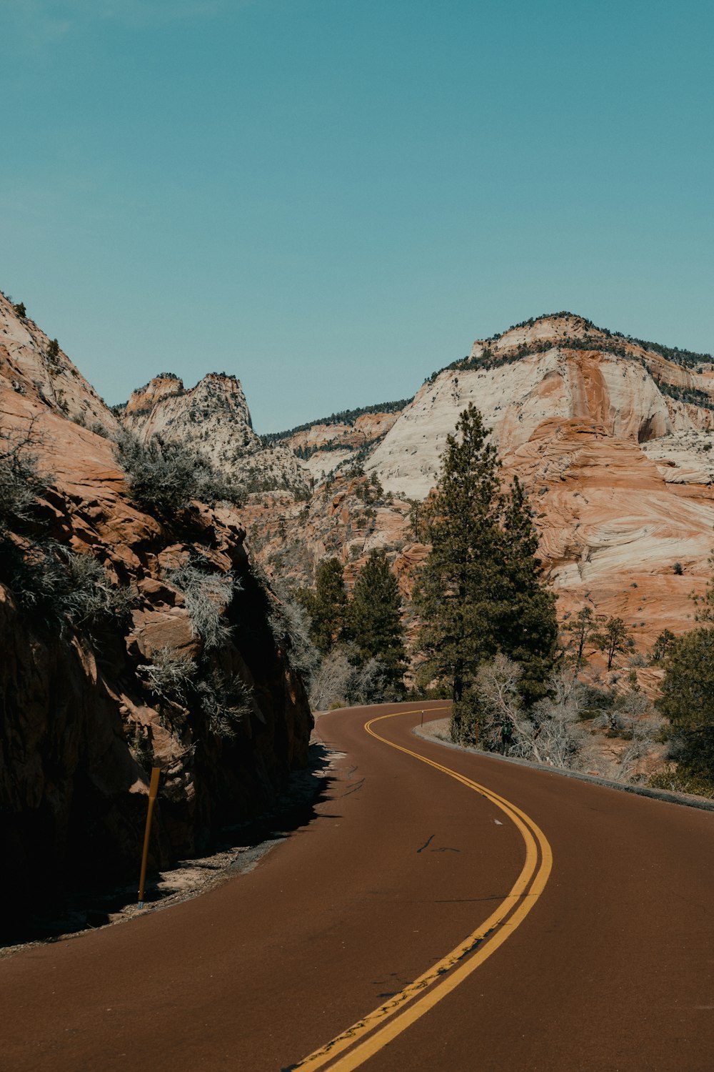 gray asphalt road between brown rocky mountain during daytime