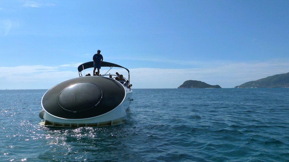 man in black shirt riding on black and white boat on sea during daytime