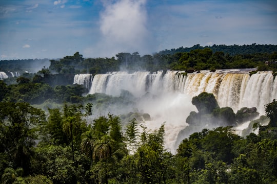 waterfalls in the middle of green trees under blue sky and white clouds during daytime in Iguazu National Park Argentina