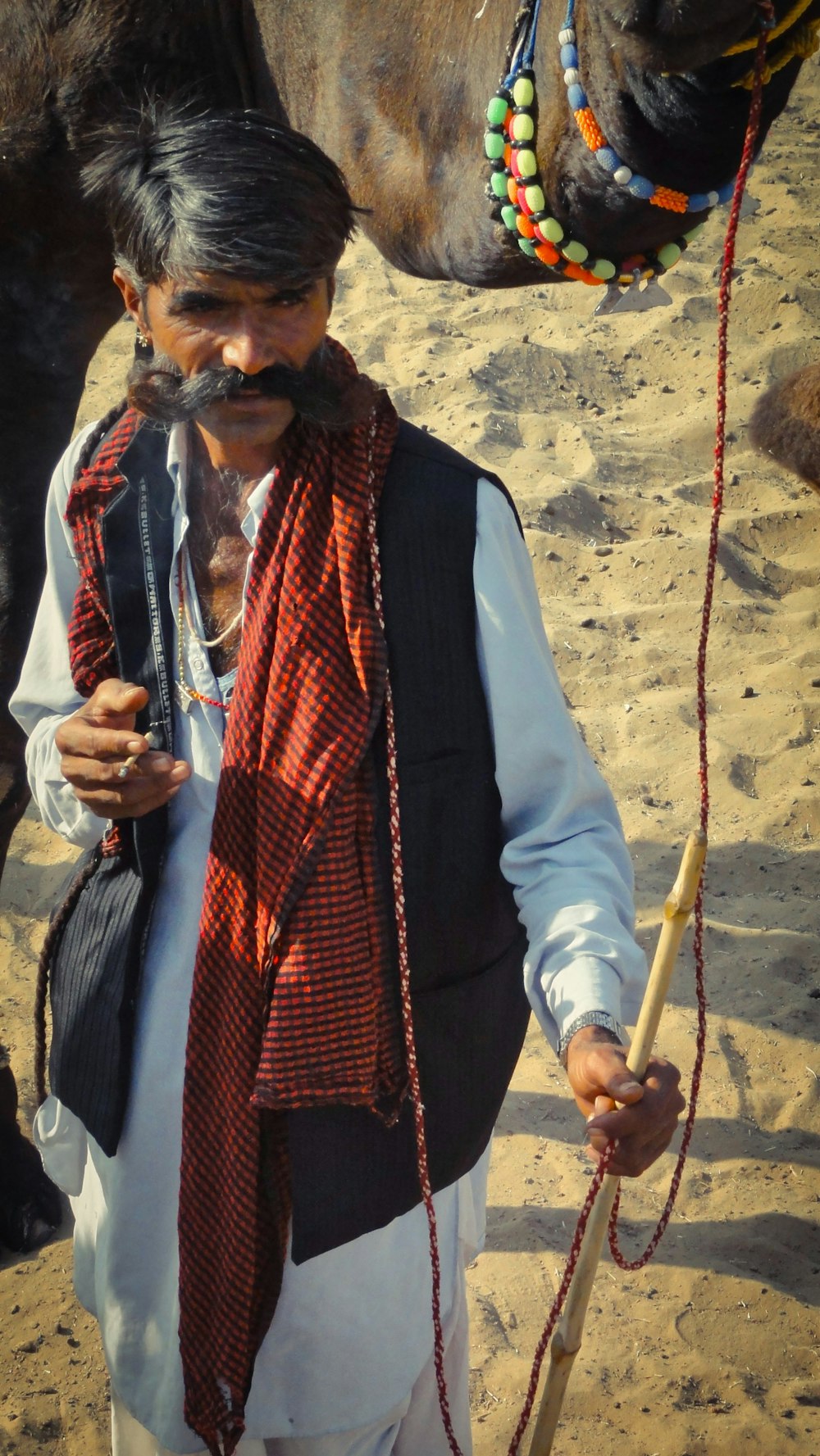 man in white dress shirt and red scarf holding brown stick