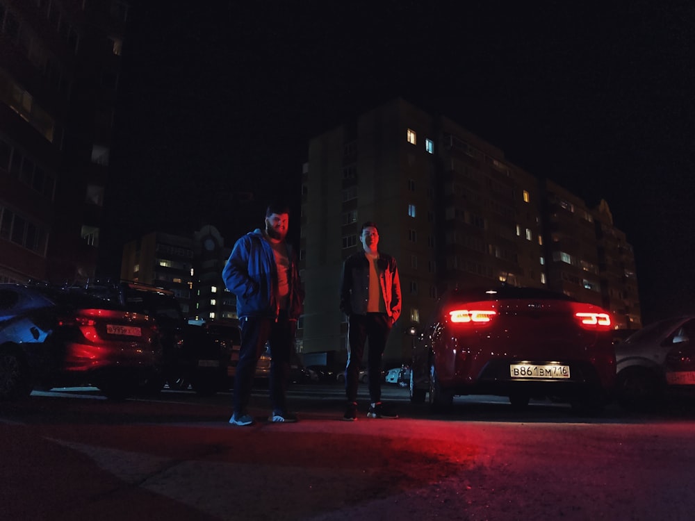 man in blue denim jacket standing beside woman in red jacket during night time