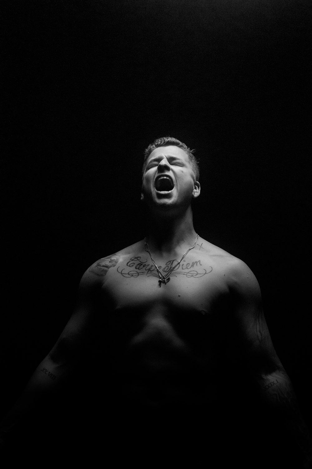 Photo en niveaux de gris d’un homme aux seins nus avec un collier en argent