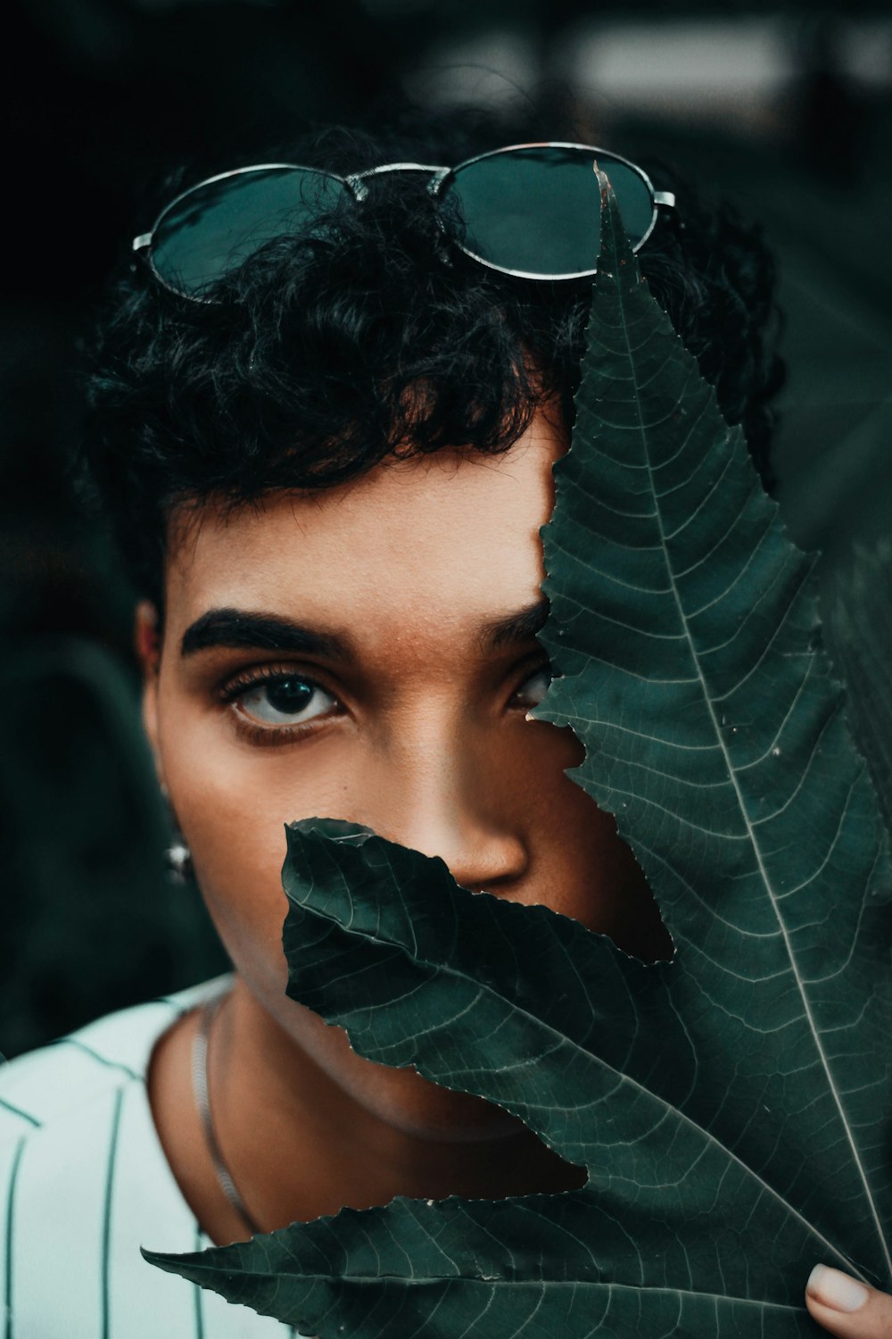 woman in white shirt with green leaves on her head