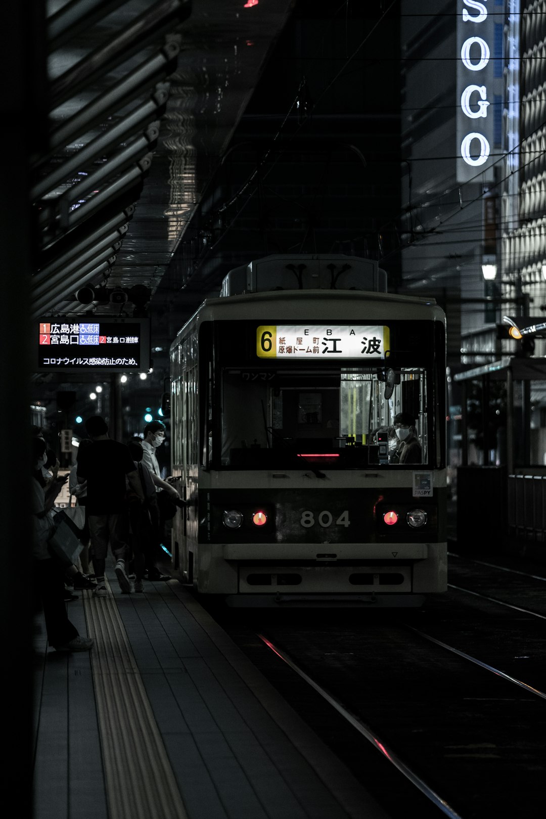 people walking on sidewalk near white train during night time