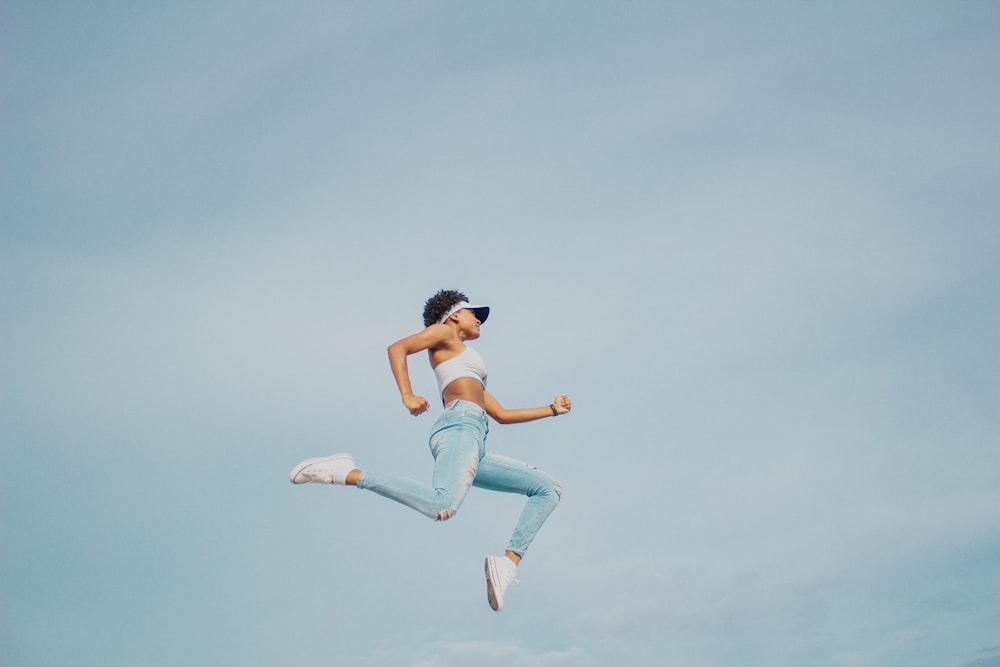 man in white tank top and blue denim jeans jumping