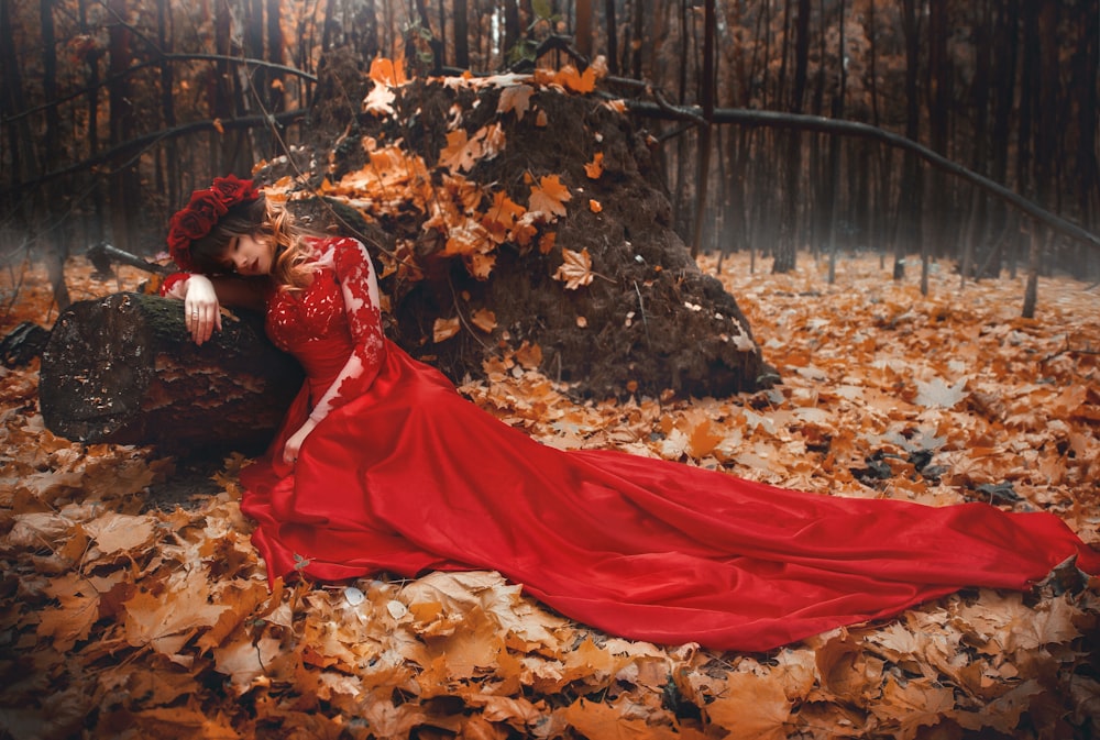 woman in red dress lying on dried leaves