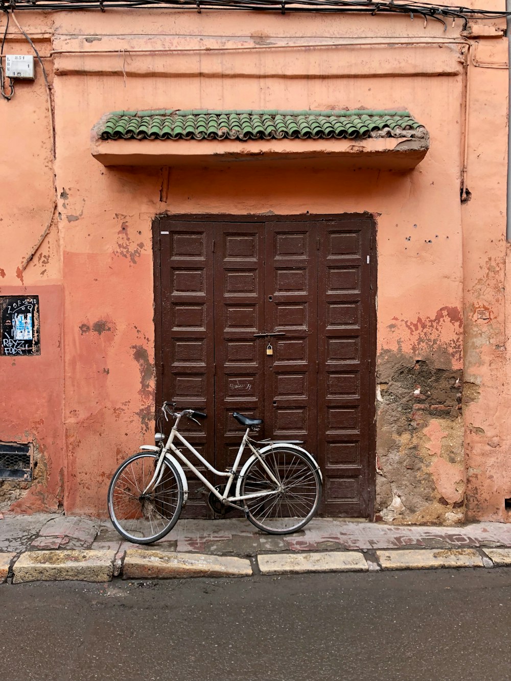 black bicycle parked beside brown wooden door