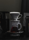 An artisan pour-over setup with fresh coffee dripping into a clear glass carafe.