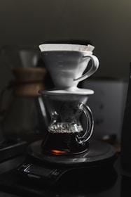An elegant ceramic pour-over dripper resting on a warm beige countertop with soft morning light.