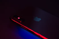 Close-up shot of a sleek smartphone glowing under multi-colored lighting.