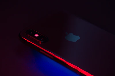 Close-up shot of a sleek smartphone glowing under multi-colored lighting.