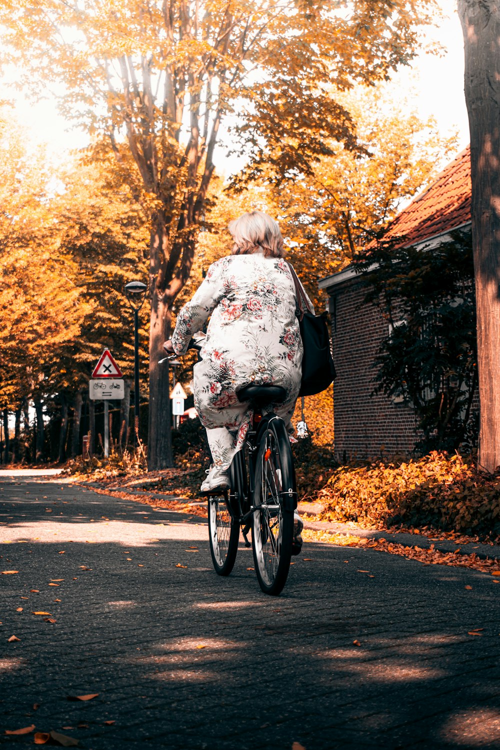 Mujer en camisa de manga larga floral blanca y negra montando en bicicleta negra durante el día