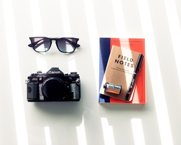 A creative flat lay of a notebook, glasses, and a camera representing journalism.