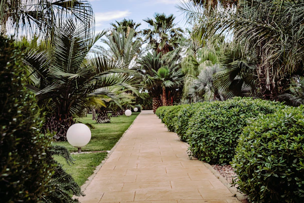 A peaceful garden path inside Jesolo Aruga resort lined with tropical flowers and hammocks.