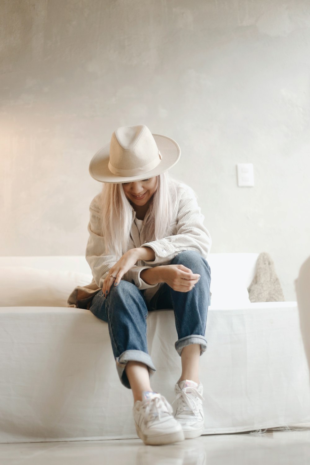 woman in white long sleeve shirt and blue denim shorts sitting on white concrete bench