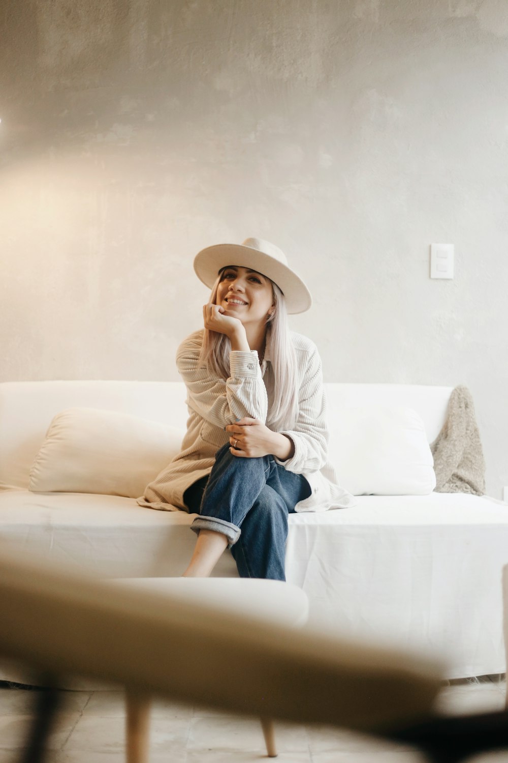 woman in white long sleeve shirt and blue denim jeans sitting on white couch