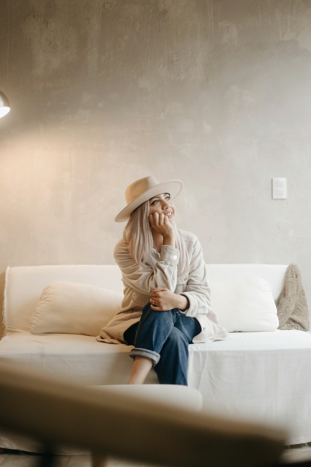 woman in white long sleeve shirt and blue denim jeans sitting on white couch