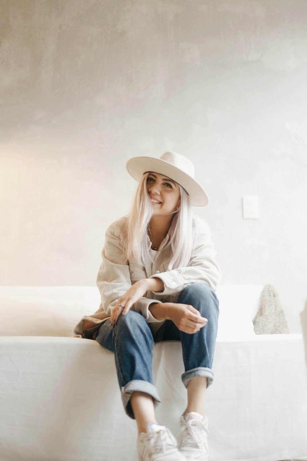 woman in white long sleeve shirt and blue denim jeans wearing white cowboy hat sitting on on on on on