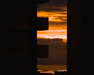 A cinematic frame capturing a dramatic sunset over an urban skyline, highlighting sharp contrasts and deep shadows.