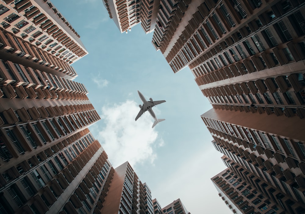 an airplane is flying through the air between tall buildings