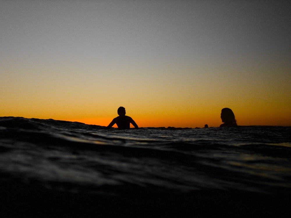 silhouette of woman in water during sunset