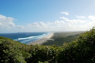 A panoramic view of white sandy beaches stretching along the coast under a bright blue sky.