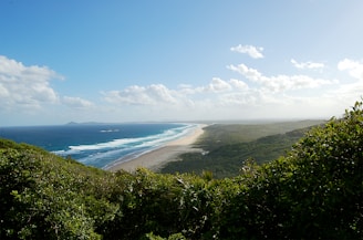 A panoramic view of white sandy beaches stretching along the coast under a bright blue sky.