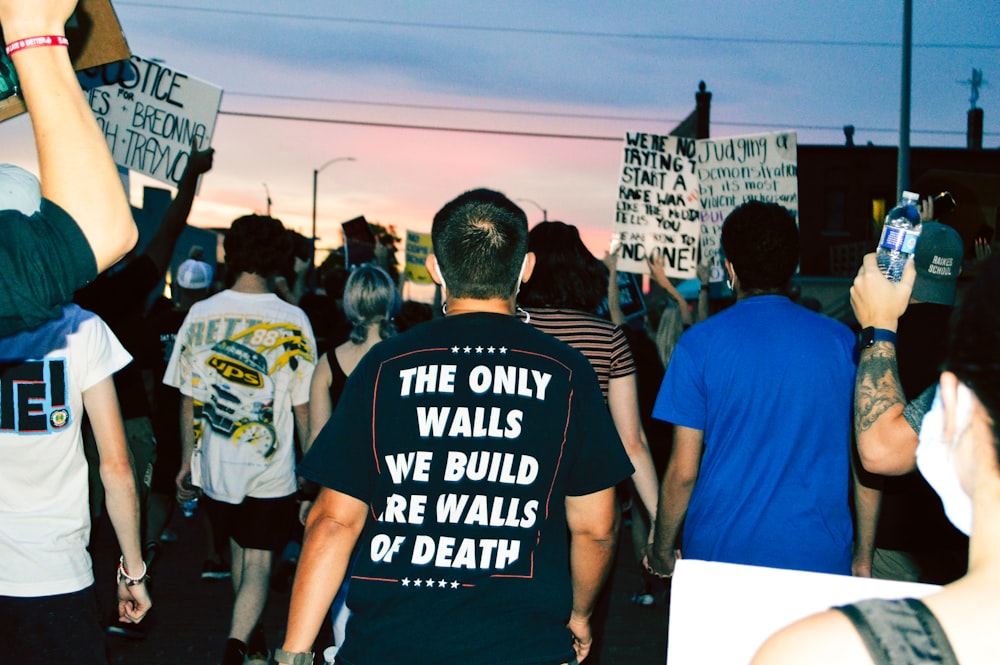 man in black crew neck t-shirt standing in front of people during daytime