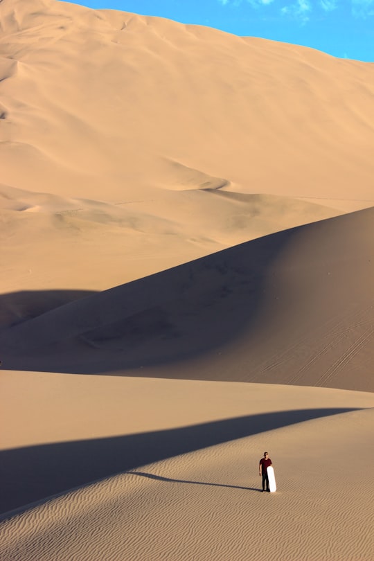 person walking on desert during daytime in Huacachina Peru