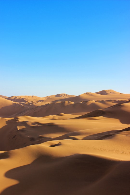 brown and white mountains under blue sky during daytime in Huacachina Peru