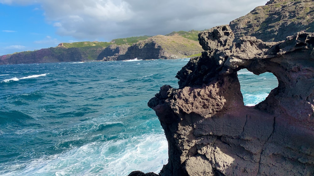 brown rocky mountain beside blue sea under white sky during daytime