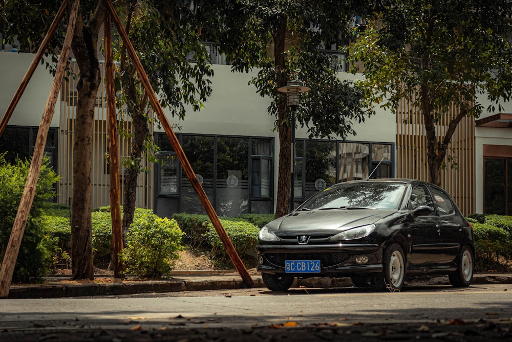 black mercedes benz coupe parked near green tree during daytime