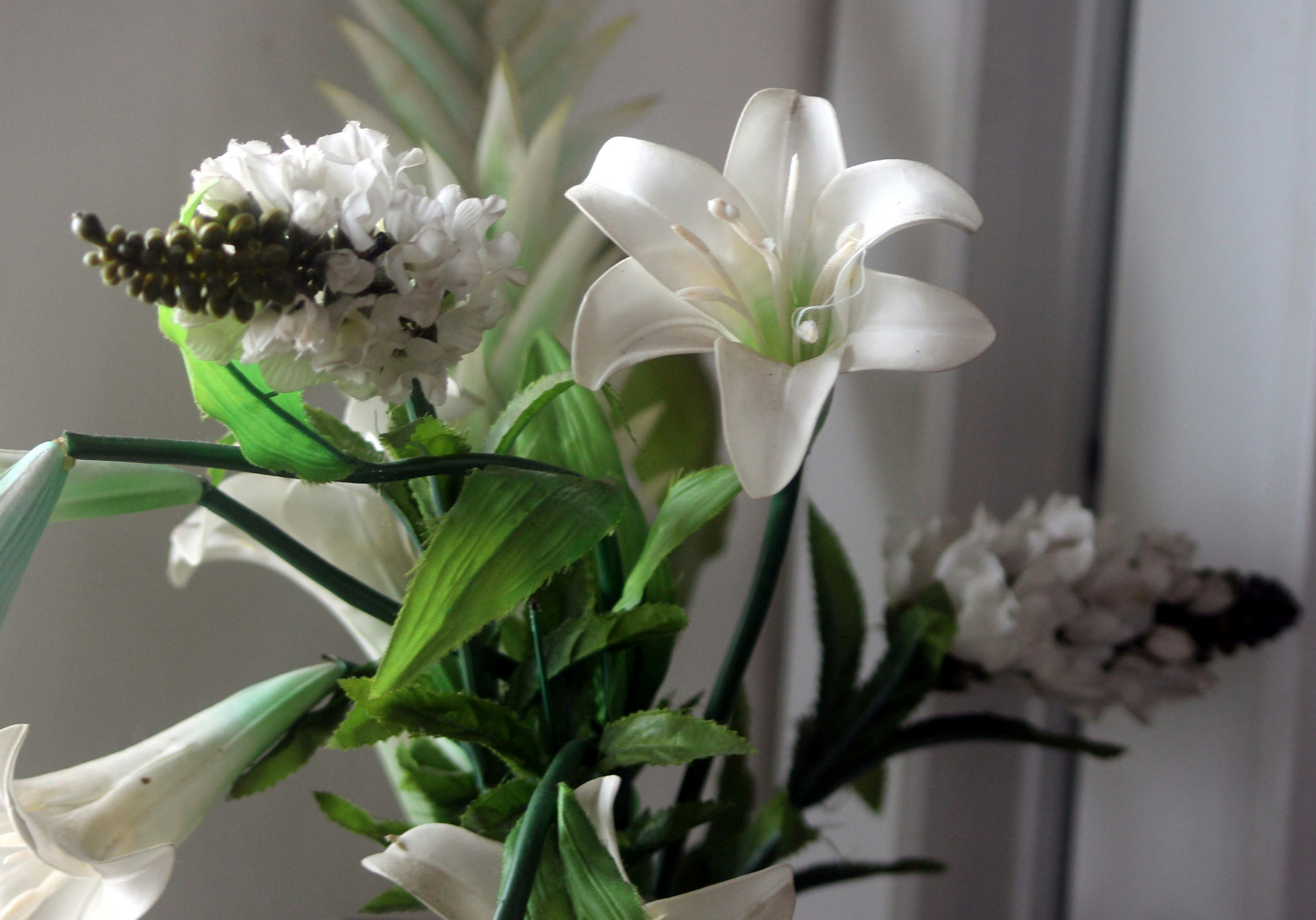 White lilies and roses in a serene sympathy arrangement, quiet soft white background