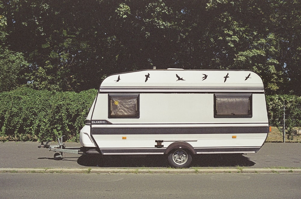 white and brown rv trailer parked on gray asphalt road during daytime