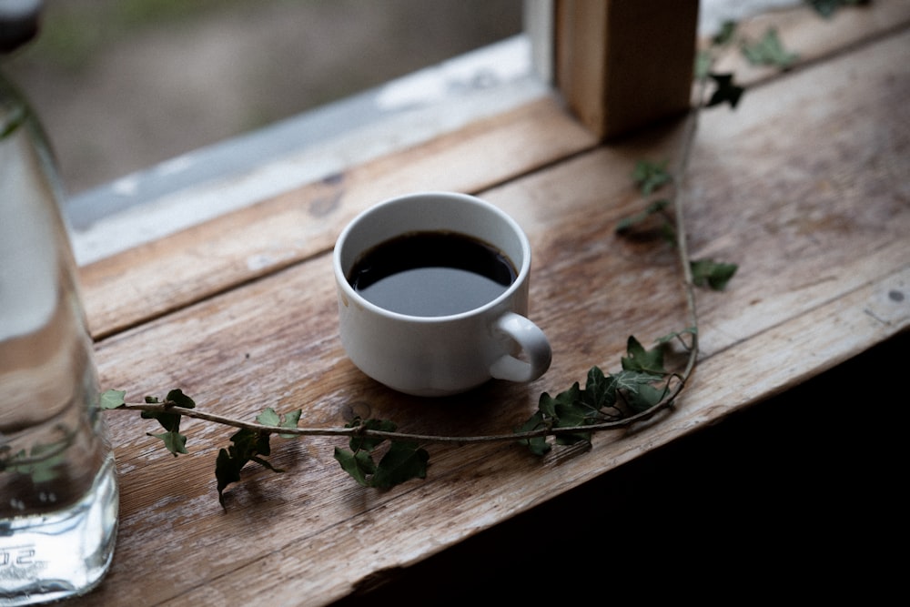 white ceramic mug with coffee on brown wooden table