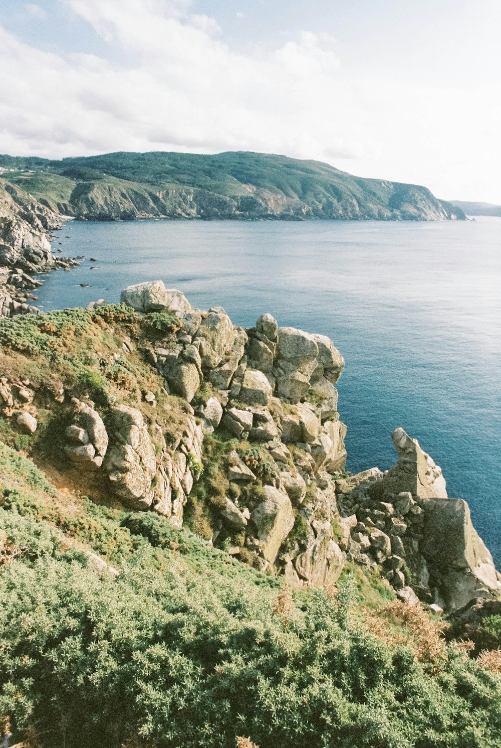 gray rocky mountain beside body of water during daytime