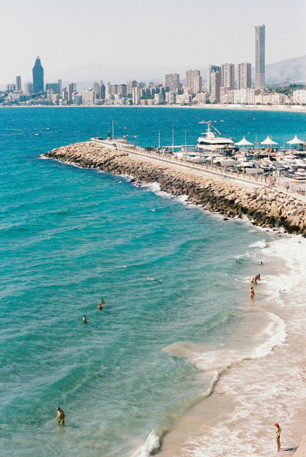 people swimming on sea during daytime