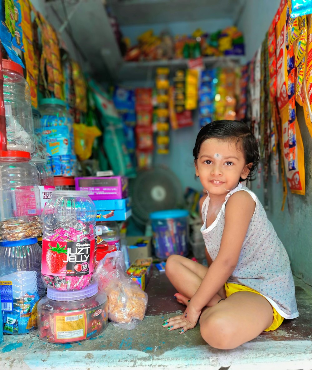 girl in white tank top sitting on floor with toys