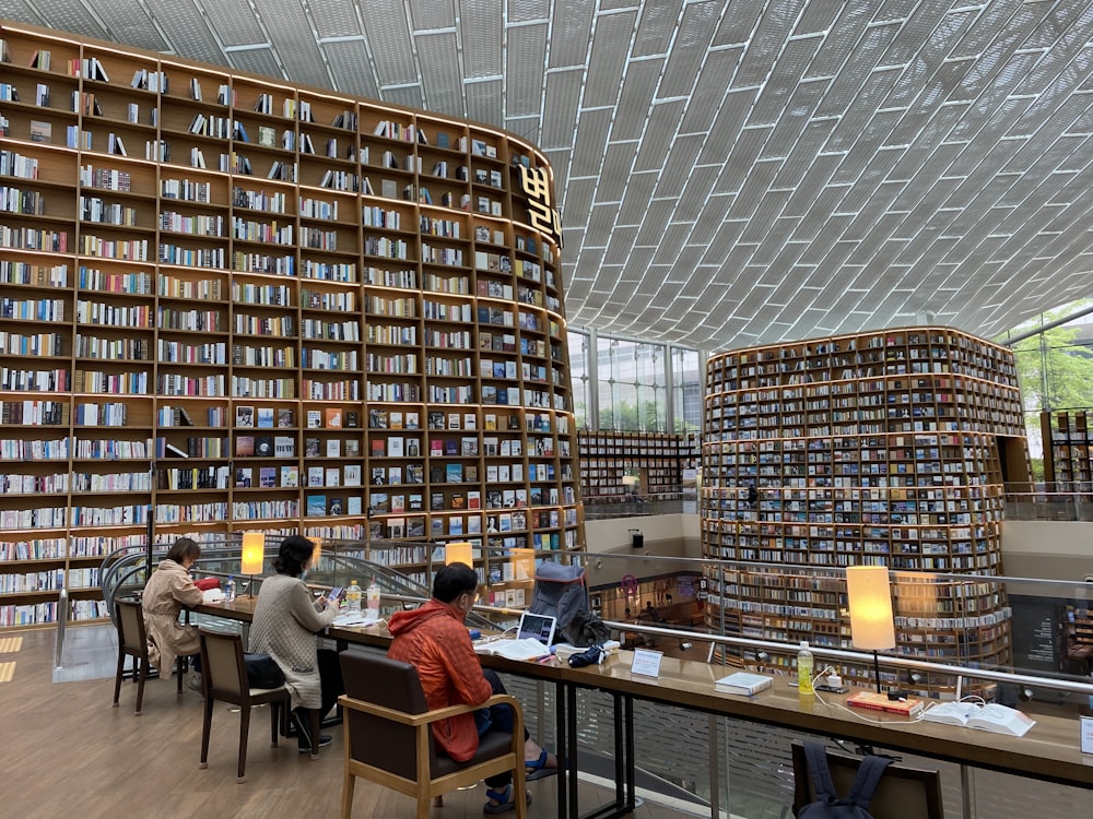 personnes assises sur une chaise devant la table à l’intérieur de la bibliothèque