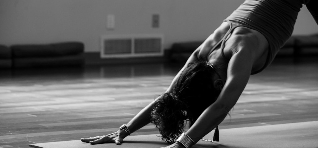 woman in black tank top and black pants bending her body on floor